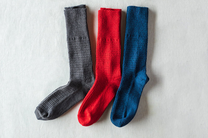 靴下のサイズは、22-24cm と 25-27cmの2種類、色は左からSUMI［グレー］、 ROUGE［赤］、 BLEU［青］の3色からお選びいただけます。