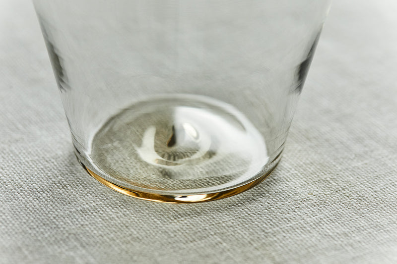 底には手吹きガラスならではの独特な波形が。淡い飴色は、表面を焼成する際にできる自然な焼き色です（＊写真はカップ クリア ショート）。